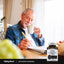 Elderly man enjoying coffee and writing next to a bottle of Activated Charcoal.