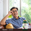 A middle-aged man smiling and relaxing on a couch next to a Beet Root bottle.