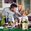 Adult man, woman, and young girl in a kitchen; the girl feeds the man berries next to a bottle of Castor Oil.