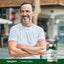 Middle-aged man smiling, arms crossed, standing next to a bottle of Chanca Piedra.
