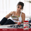 Young woman enjoys a salad at a kitchen counter with a bottle of Cleansing Cranberry Gummies nearby.