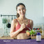 Young woman in a kitchen holds a salad bowl and Detox Lean Cleansing Complex bottle, suggesting healthy living.