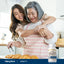 Two adult women are hugging and smiling while preparing croissants in a kitchen, with a Digest-IT bottle on the counter.