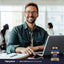 A smiling young man sits at a desk working on a laptop, next to a bottle of GHR Complex.