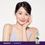 Smiling young woman posing with her hand on her chin next to a bottle of Grapeseed Oil.