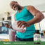 Young adult Black man smiling while pouring a smoothie into a glass, with a Grass Fed Beef Organs bottle beside him.