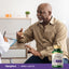 An elderly Black man talks to a doctor next to a bottle of Herbal Laxative.