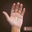 A white and clear capsule rests on a hand. A scale shows the capsule measures 1 inch or 2.54 cm in length.