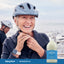 An older woman adjusts her bike helmet next to a bottle of Magnesium Oil.