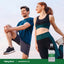 Young man and woman stretch outdoors, holding a bottle of Magnesium Oil for muscle relaxation.