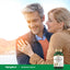 A middle-aged couple smiling and embracing outdoors with a bottle of Odorless Garlic.