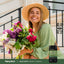 Smiling young woman holds a large bouquet of flowers next to a bottle of Calm Caps.