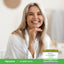 Lifestyle image of a smiling adult with a Piping Rock Cucumber Cream, 4 oz. (113 g), displayed in the bottom right corner