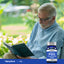 An elderly man sits reading a book next to a bottle of PQQ.