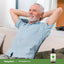 Older man relaxing with his hands behind his head on a couch, next to a bottle of Peppermint Oil.