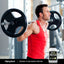 A man lifts a barbell in a gym, accompanied by a tub of Organic Plant-Based Protein, showcasing fitness and nutrition.