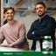 Two men smiling, one seated at a desk, the other standing, with a Prostaid Herbal Complex bottle.