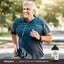 An older man jogging outdoors while holding Pumpkin Seed Oil, showcasing an active lifestyle and the product's potential health benefits.