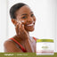 Young woman applying cream to her face with a jar of Retinol Cream beside her.
