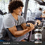 Young man doing bicep curls in the gym with a Mega T 1000 bottle nearby.