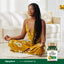 A young Black woman meditates on the floor with an Ultra Peppermint Oil bottle beside her.